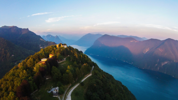 A warm glowing sunset over Monte Bre's summit, seen from a drone. Lugano, Switzerland.